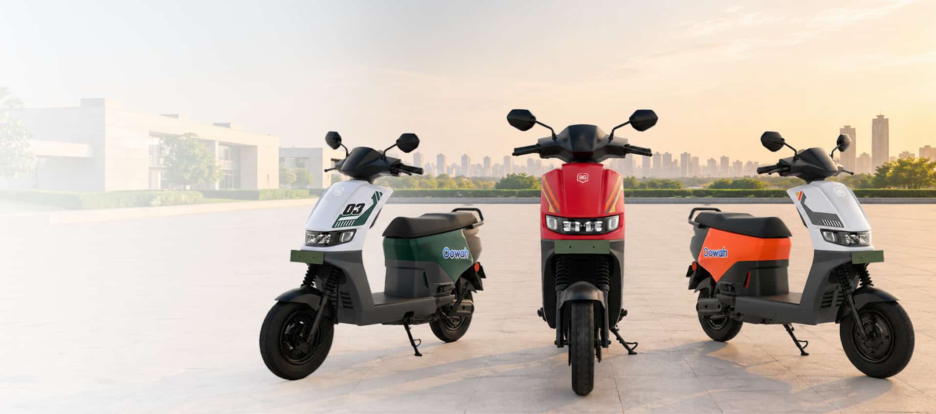 Three BG Oowah electric scooters — white, red and orange — parked side by side on a rooftop at sunset.